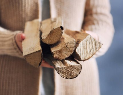 Kvinde i beige cardigan bærer træ i hænderne